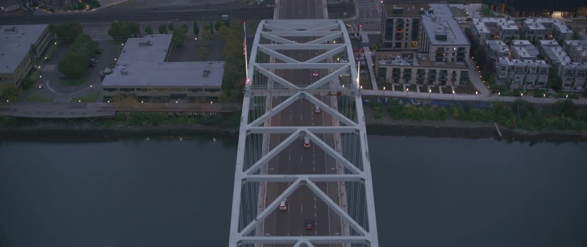 Vehicles driving over a bridge towards a city