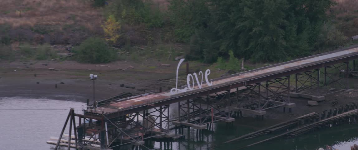 A love sign is displayed on a metal pier on the water