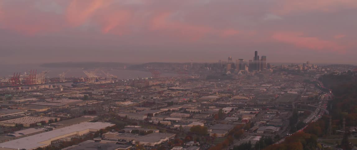 Traffic moves on the highway toward the city at sunset