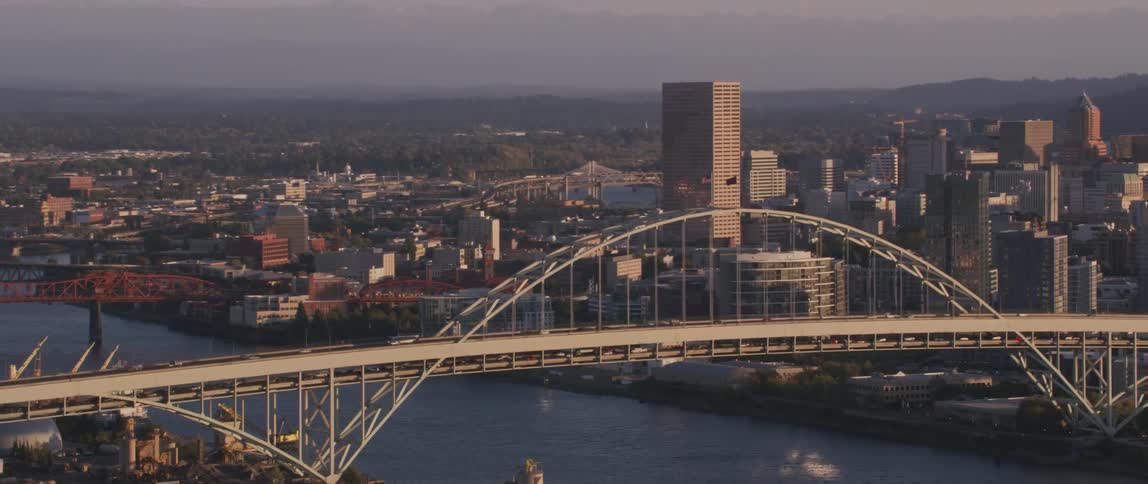 Vehicles driving over a bridge towards a city