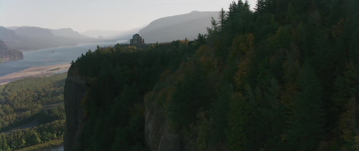 The sun shines on a tall cliff by the water