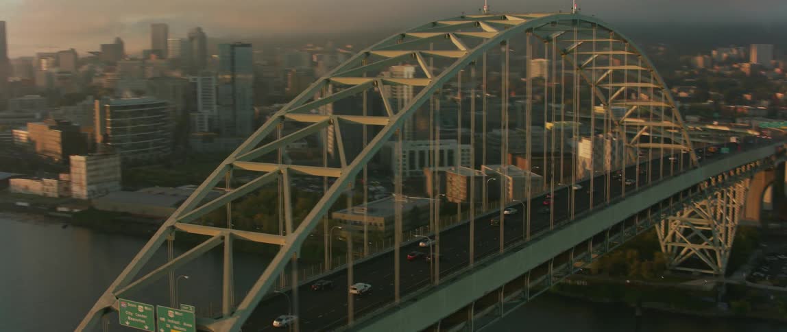 Vehicles driving over a bridge towards a city
