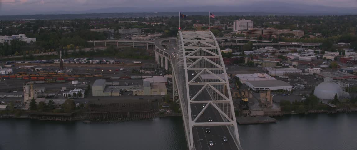 Cars drive on a city bridge at sunset