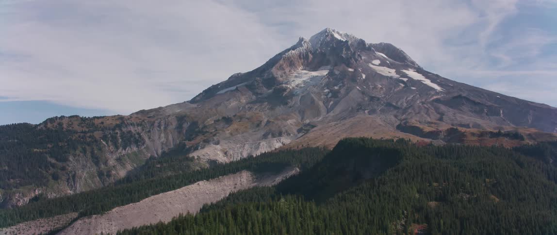 The mountain peak overlooks the forest on the slopes
