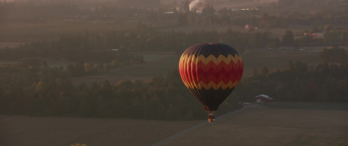 A hot air balloon is sailing at dusk