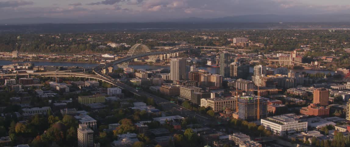 A large city with a body of water and cars driving over a bridge