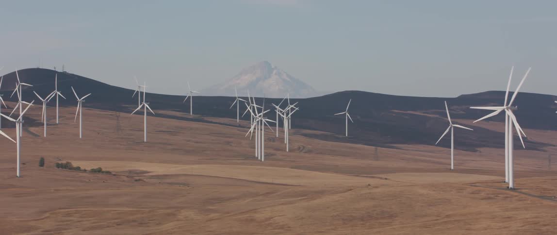 Wind turbines are rotating as they operate on a hillside during the day