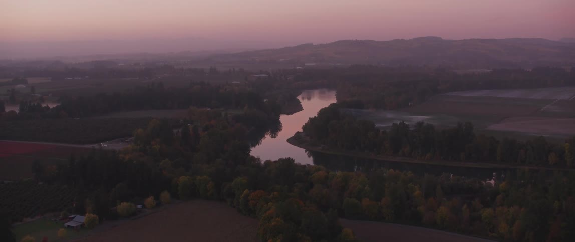 A river flows through a rural landscape at sunset