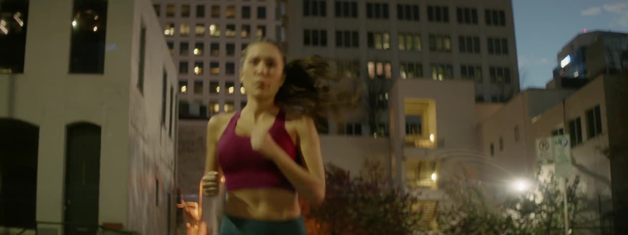 A female athlete is jogging in an urban setting at night