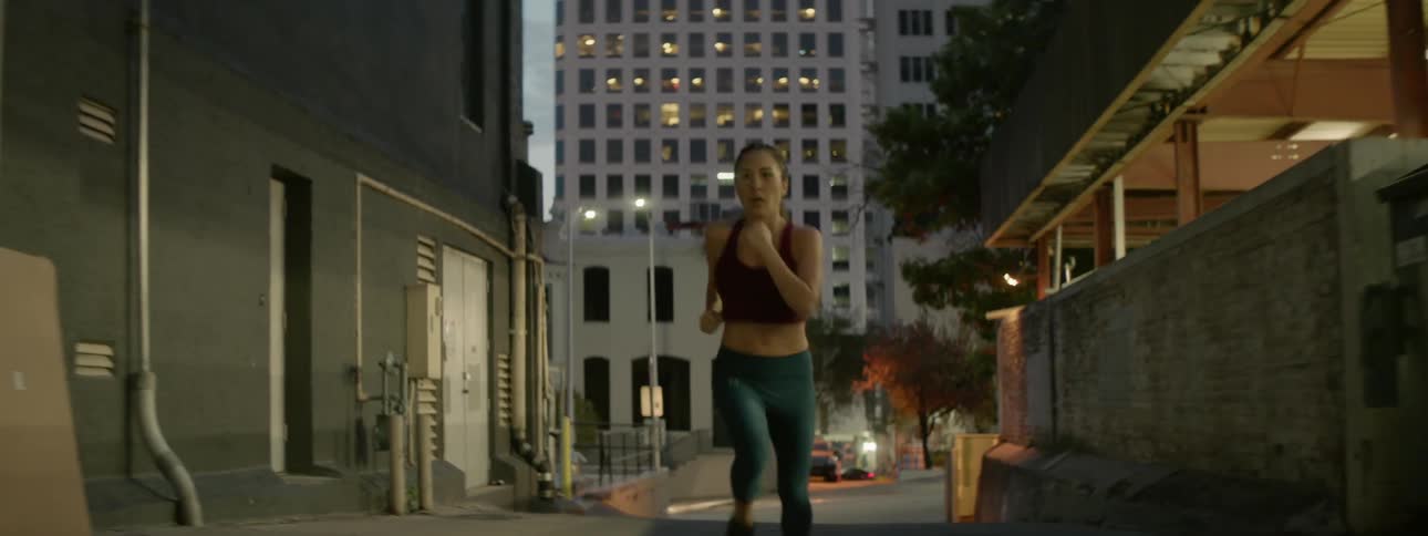 A woman jogs up a city street