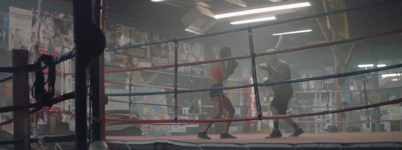 A boxer trains in the ring with a coach