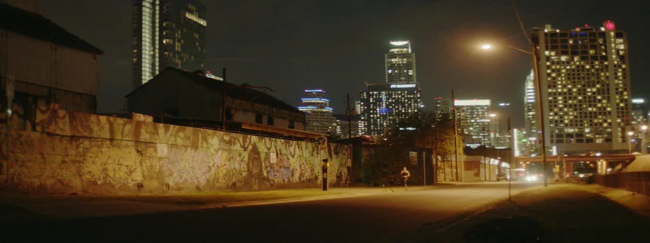 A person jogs down a city street at night