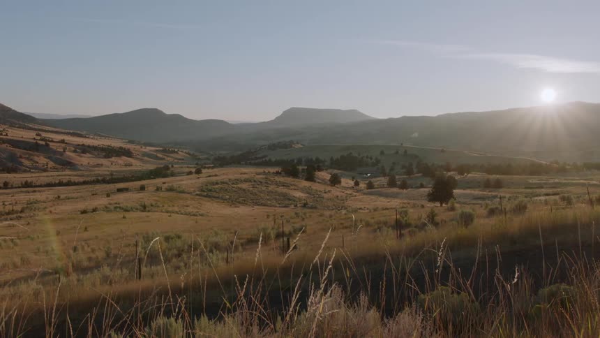 The sun is rising over a valley on a sunny day