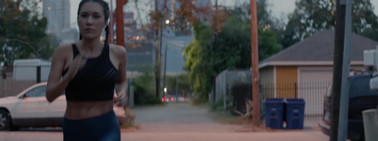 A woman jogs on a city sidewalk