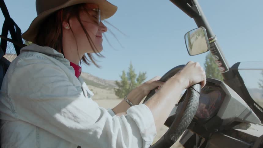 A woman is driving a vehicle in a desert on a sunny day