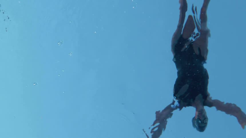 Person diving into a pool of water as seen by their reflection