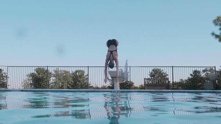 A woman dives off a board and into a swimming pool