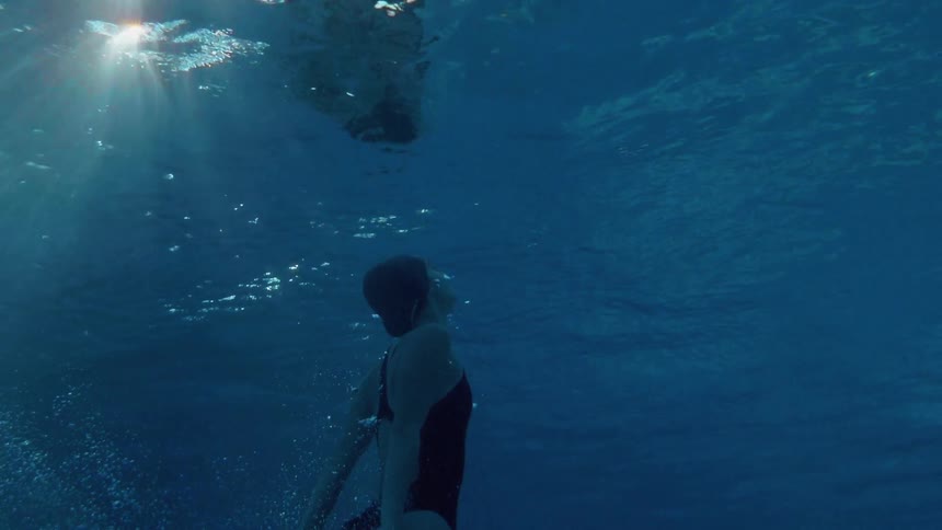 A woman floats straight up and pushes her head out of the water