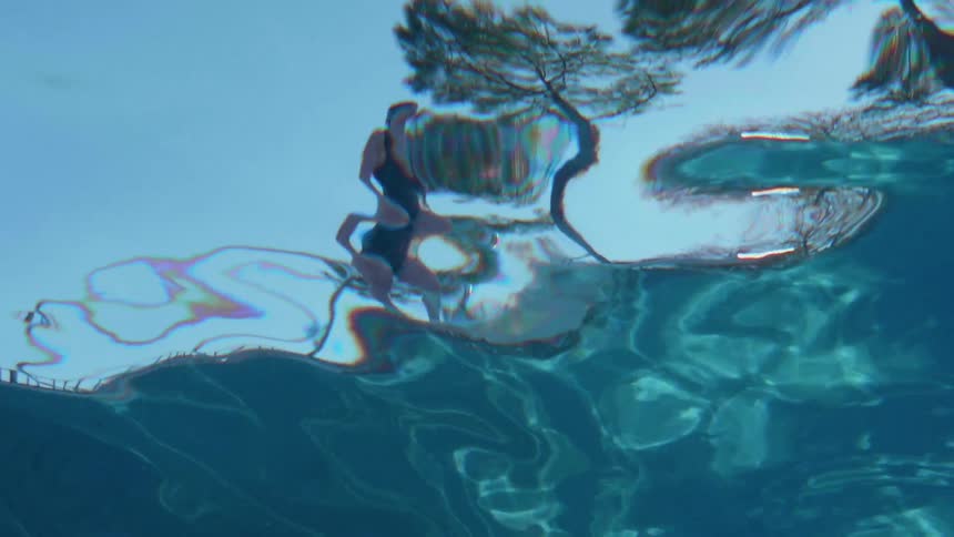 A woman stands on the edge of a swimming pool