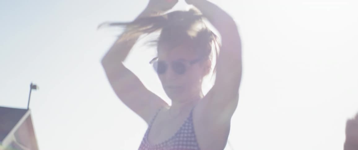 A woman is twirling around in circles outside on a sunny day