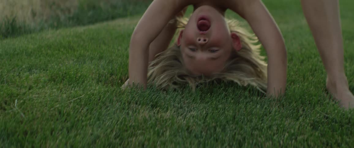 A young boy does a handstand in the grass