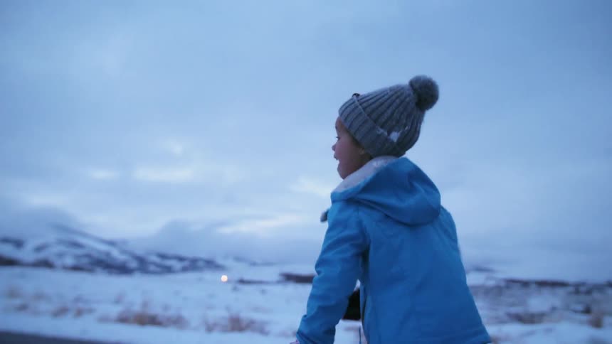 A child is running outside at dusk in winter