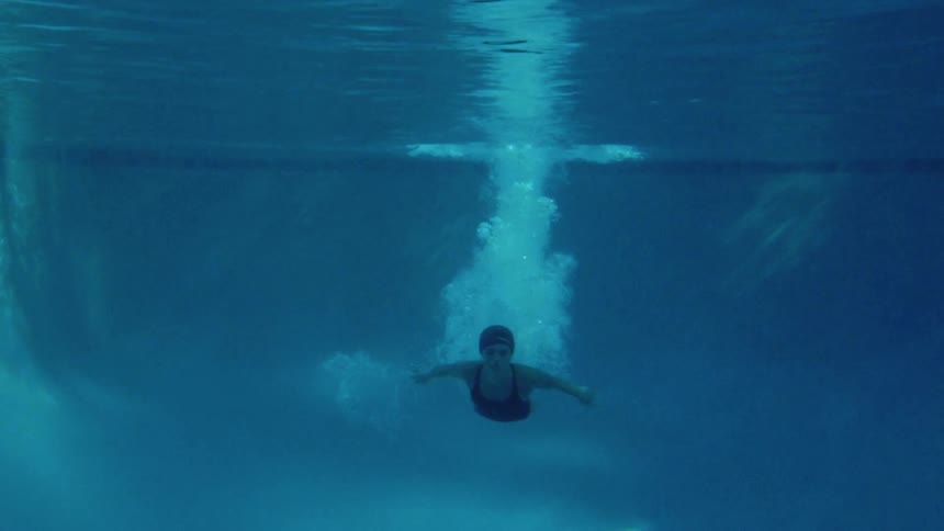 A woman dives into the deep end of a pool