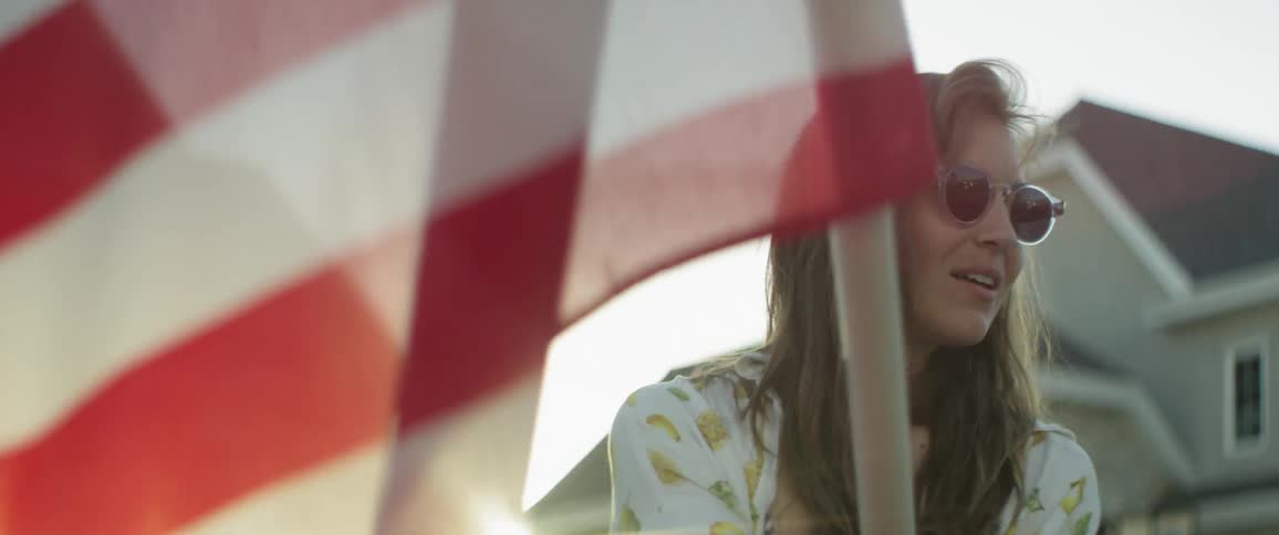 A woman in sunglasses waves the american flag