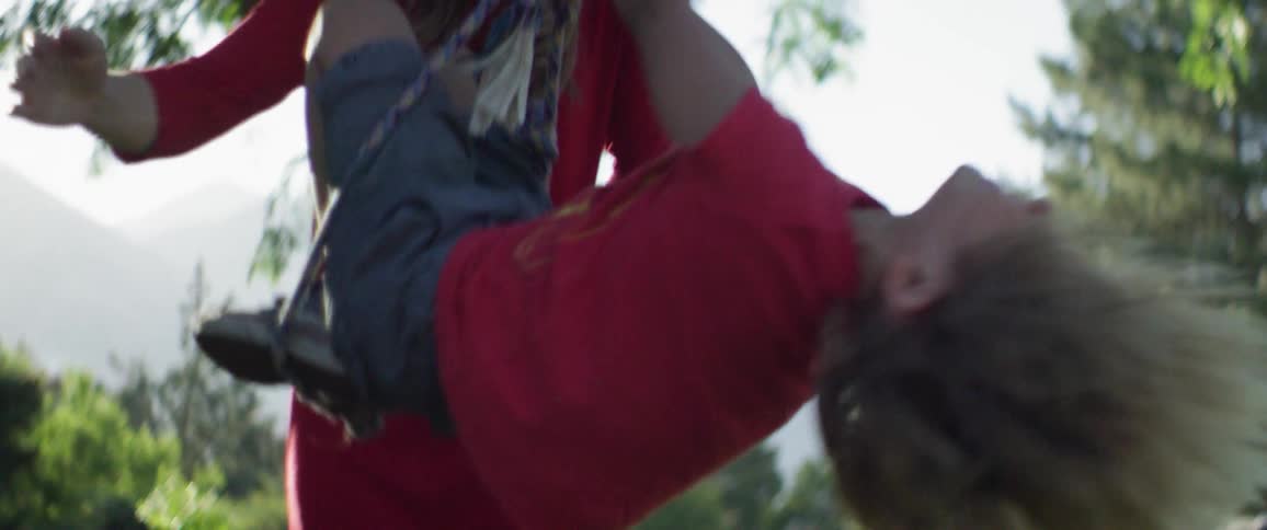 A woman twirls her son on a rope swing in the yard