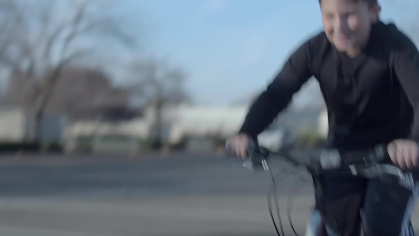 Children ride bikes and a scooter down the street