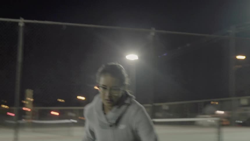 A woman kicks a ball at night