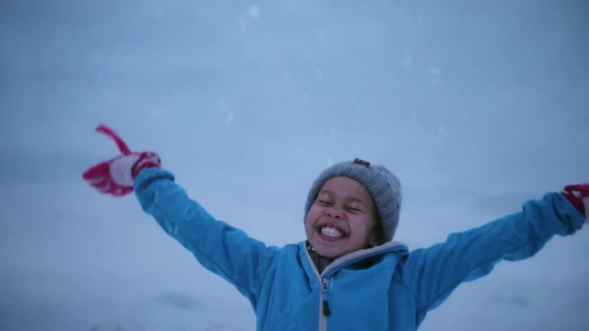A girl smiles and plays in snow