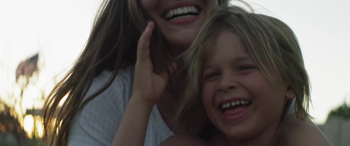 A woman hugs a young child while smiling