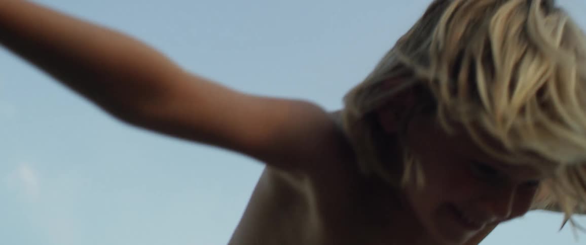 A shirtless boy balances on a woman's feet