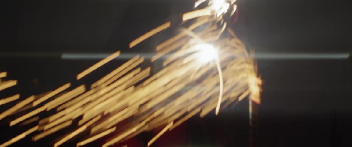 A girl is laughing and smiling as she holds a sparkler outside at night