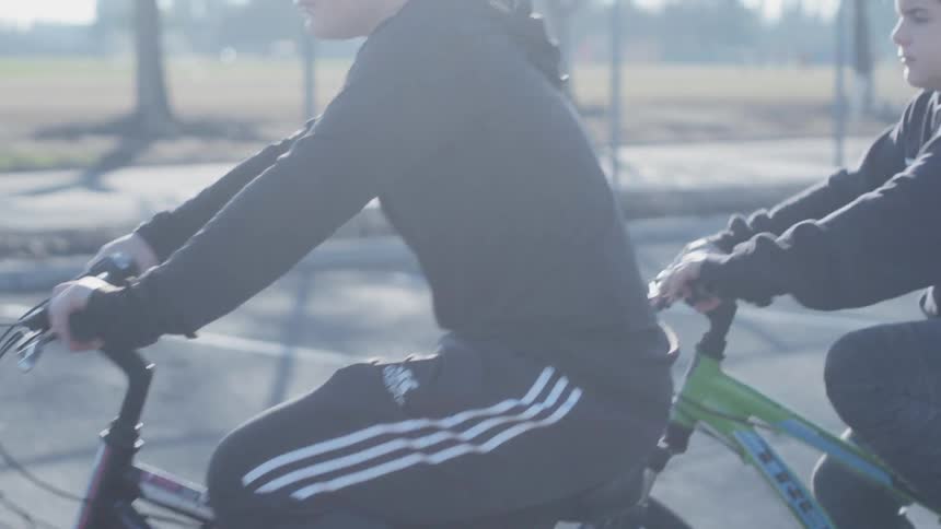Boys ride bicycles in a parking lot