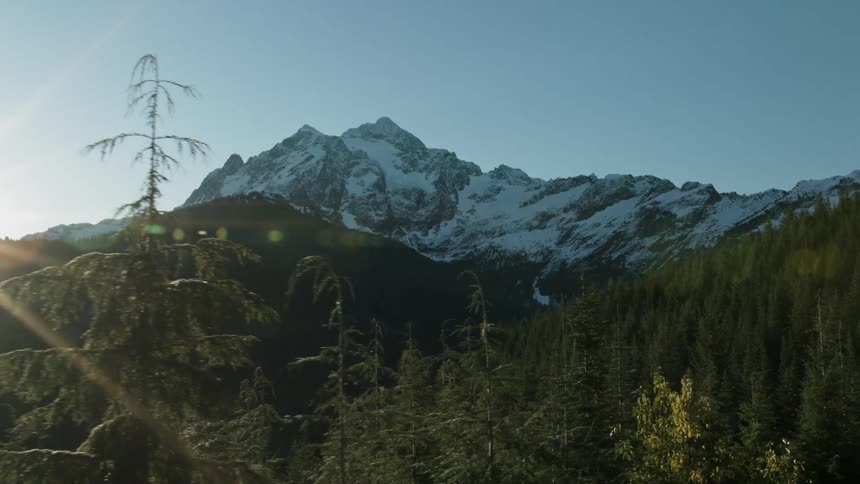 Trees cover the snowy valley between mountains