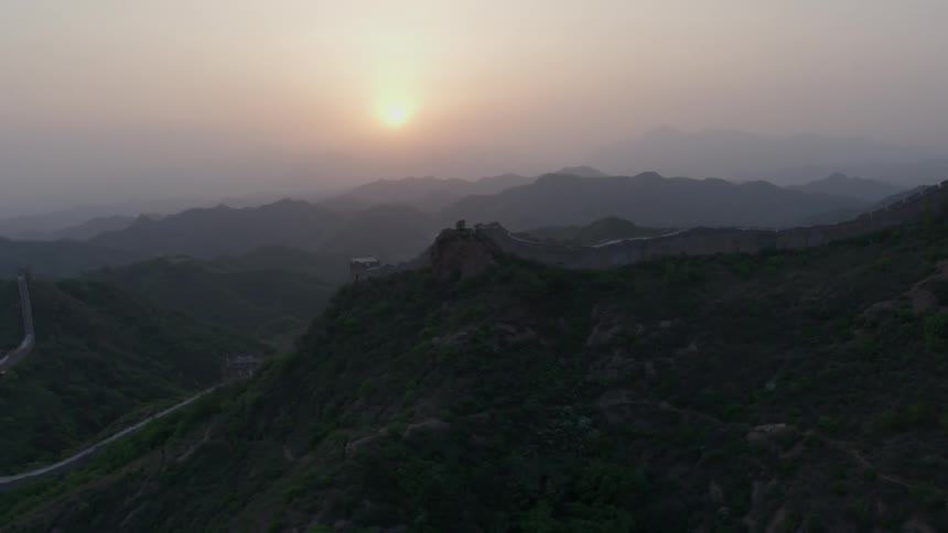 The sun is rising in the sky over the great wall in china
