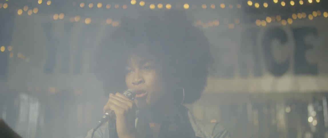 Smoke blows past a woman singing on stage
