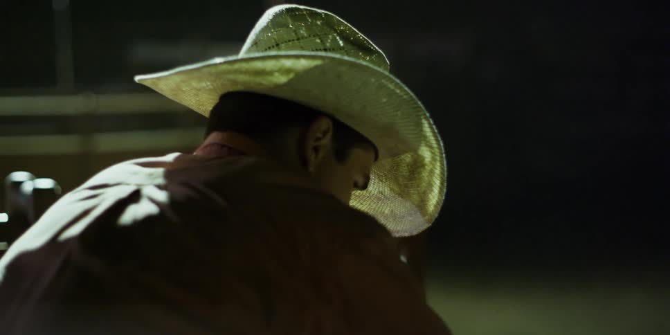 A man in a cowboy hat adjusts his seat
