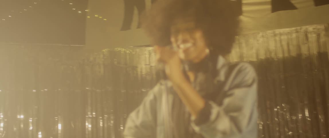 Woman smiling and standing on stage behind a microphone
