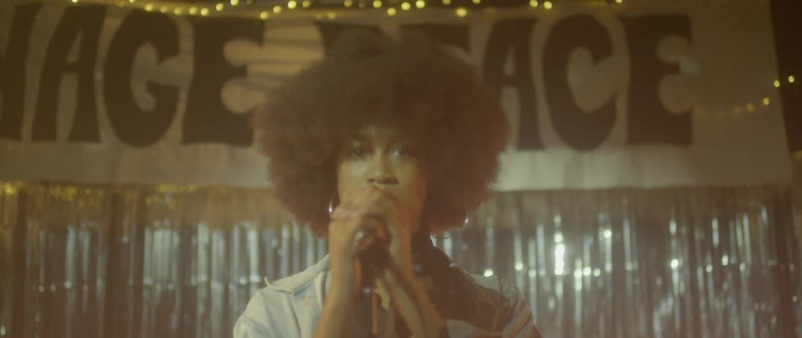 A woman sings into a microphone on stage