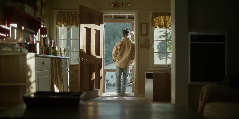 A man leaning against the doorway walks out