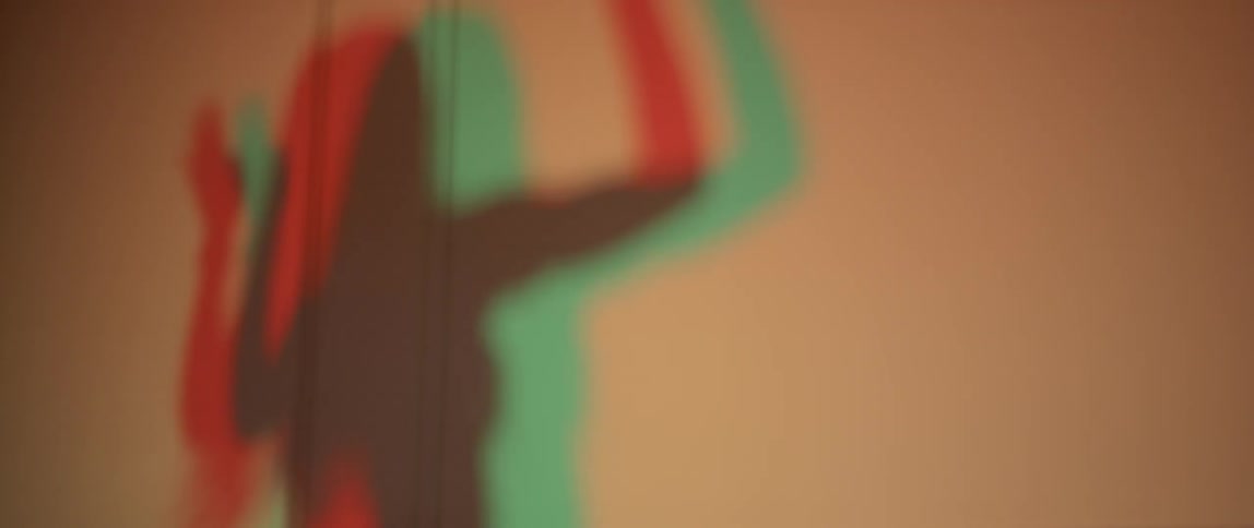 A dancing woman casts her shadow on a wall