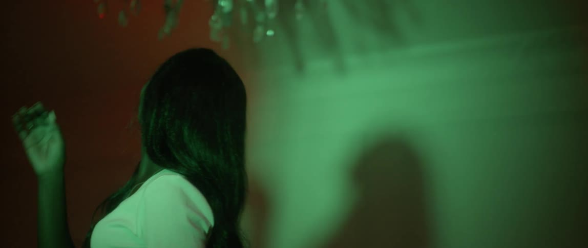 A woman is looking up at the ceiling and brushing her hair back