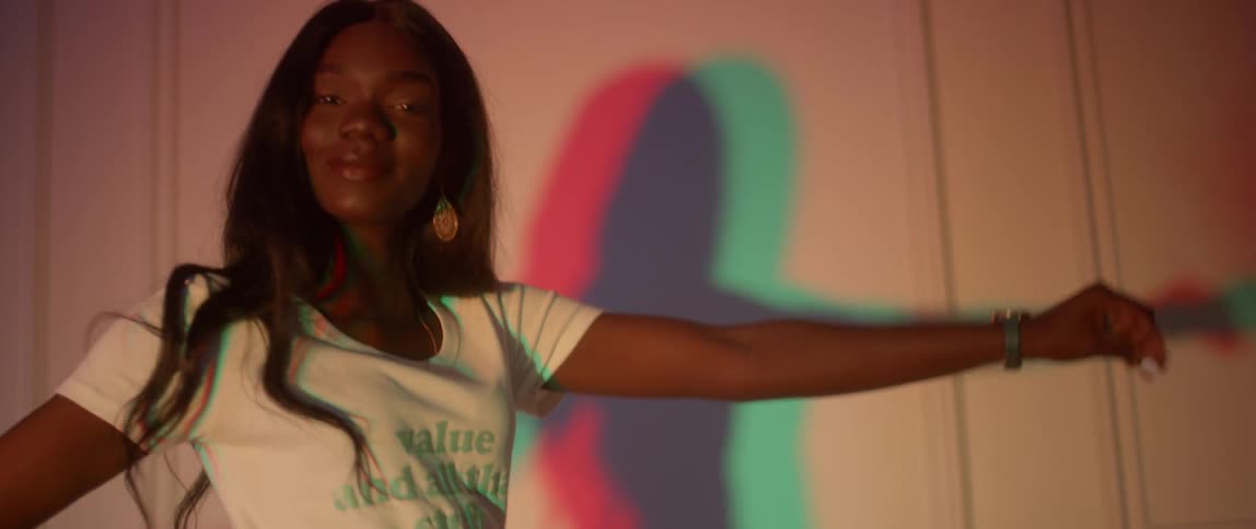 A woman dances and struts in front of the wall