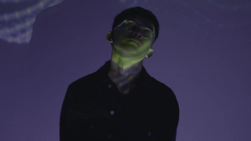 A man sways as lights and images are projected on him
