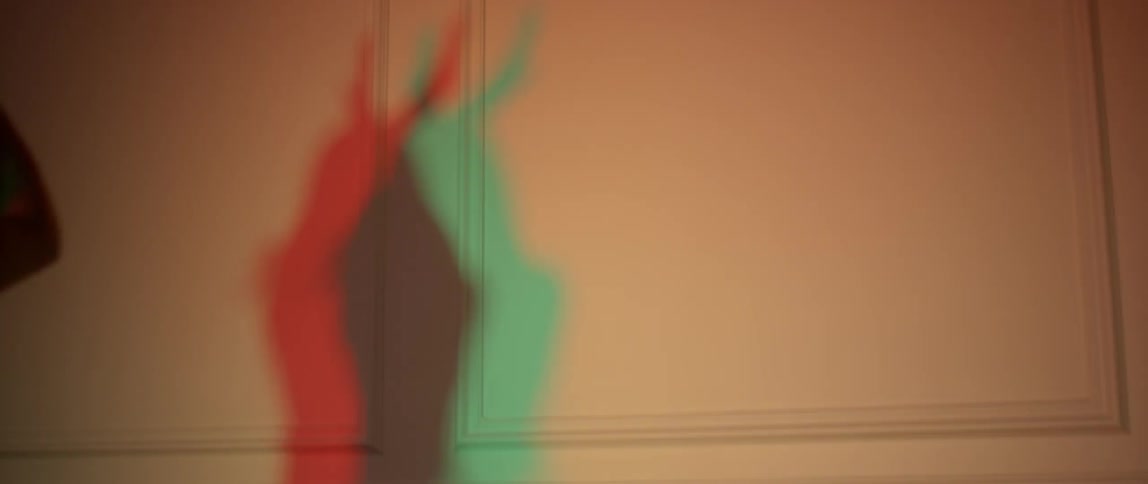 A woman with green and red shadows dances