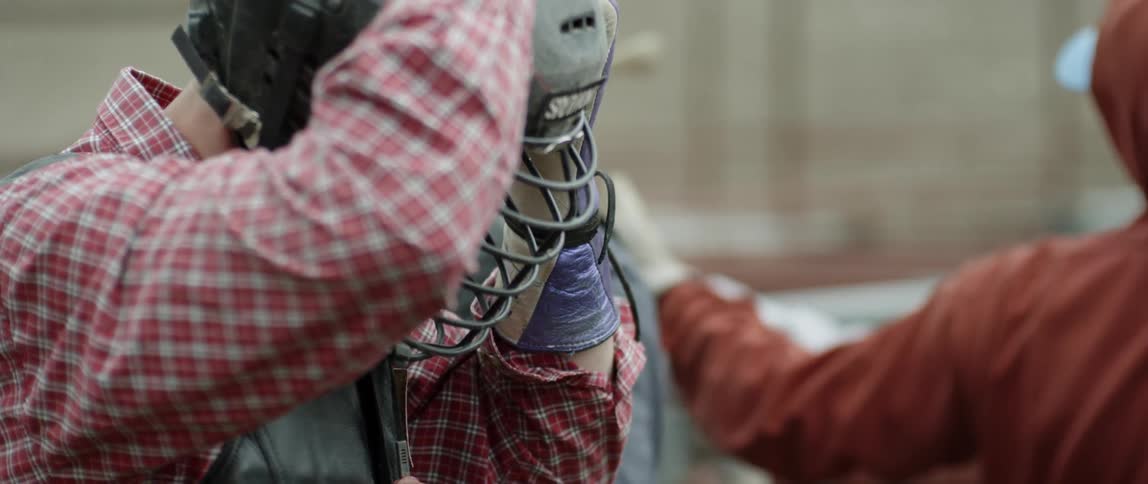 A man is adjusting his helmet as he stands outside during the day