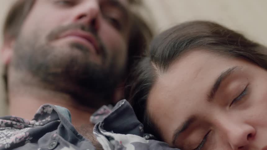 A man lies awake as a woman rests on his shoulder